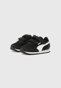 Ασπρόμαυρα παπούτσια για μωρά Puma με διπλά λουράκια με βέλκρο και επενδυμένες σόλες σε απλό φόντο.