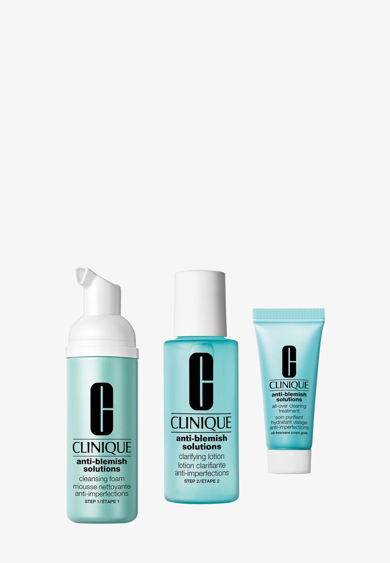 Trois produits Clinique anti-imperfections dans un emballage bleu : mousse nettoyante, lotion clarifiante et traitement global purifiant.