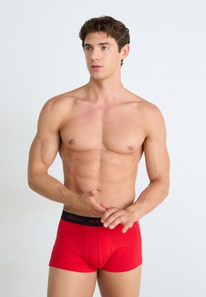 Boxers en coton rouge avec une taille noir comportant le logo "HUGO". Texture lisse, design ajusté et longueur de jambe courte.