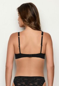 Sutien din dantelă neagră, cu bretele ajustabile, închidere cu cârlig și modele florale. Textură netedă cu detalii cu margine ondulată.
