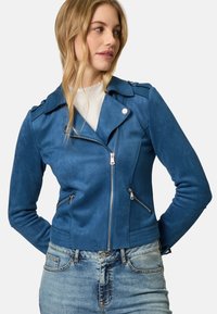 Giubbotto da motociclista blu in suede sintetico con colletto a contrasto, chiusura con zip, doppie tasche laterali e finitura testurizzata. Indossato sopra una maglietta bianca.