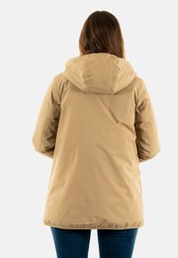 Chaqueta beige con capucha y corte relajado, hecha de un material suave y resistente al agua. Puños y dobladillo elásticos para mayor confort.