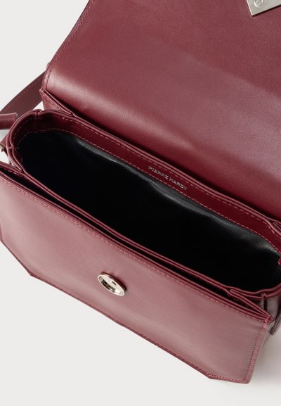 Ανοιχτή τσάντα χιαστί από δέρμα μπορντό με μαύρο εσωτερικό και ασημένιο κούμπωμα, που δείχνει την κενή κύρια θήκη και το καπάκι.