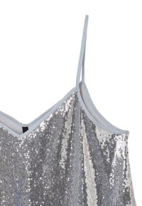 Top senza maniche in paillettes argento con scollatura a V. Sottostrato in tessuto morbido e spalline azzurro chiaro esaltano la texture scintillante.