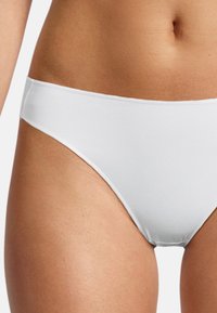 Parte inferiore di bikini bianca realizzata in materiale morbido ed elastico. Presenta un design a vita bassa e una superficie liscia senza motivi o accessori visibili.