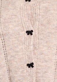 Jasno beżowy sweter z dzianiny, wykonany z miękkiej włóczki, z czarnymi, ozdobnymi kokardkami z przodu oraz teksturowanym detalem ryfli.