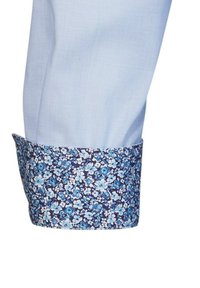Manica di camicia azzurra chiara con polsino a fantasia floreale in blu navy e tonalità di blu. Il polsino presenta un design floreale distintivo e una vestibilità rilassata.