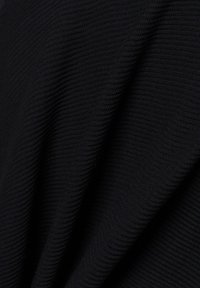 Schwarzer gestrickter Stoff mit gerippter Textur, der weiche Falten und subtilen Glanz zeigt. Das Material wirkt leicht und dehnbar.