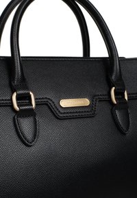 Zwarte gestructureerde handtas van getextureerd leer, met gouden hardware, dubbele handvaten en een merkembleem aan de voorkant.