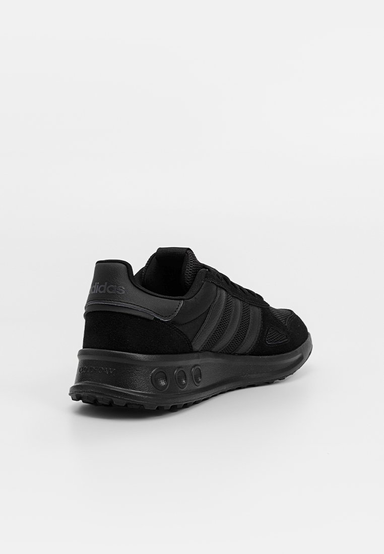 Scarpa sportiva nera con parte superiore in mesh e suede, tre strisce laterali, suola imbottita con accenti circolari e design slanciato.
