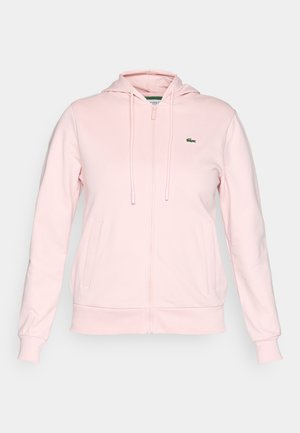 Lys rosa zip-up hettegenser laget av mykt stoff, med hette, snor, to frontlommer og en liten grønn logo på venstre bryst.
