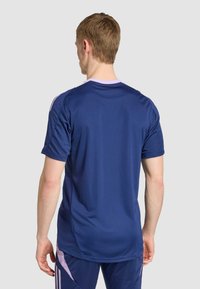 Námornícky športový dres s krátkymi rukávmi, so svetlofialovým golierom a akcentmi. Hladká textúra, súčasť zodpovedajúceho teplákového súpravy.