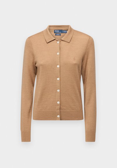 Vaaleanruskea neulecardigan, jossa on polo-kaulus, pitkät hihat ja napitus. Valmistettu pehmeästä materiaalista, ja rinnassa on pieni logo.