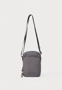 Bolso bandolera de nylon gris con un patrón de rejilla texturizada, compartimentos duales con cremallera, correa ajustable y acento amarillo en el tirador de la cremallera.