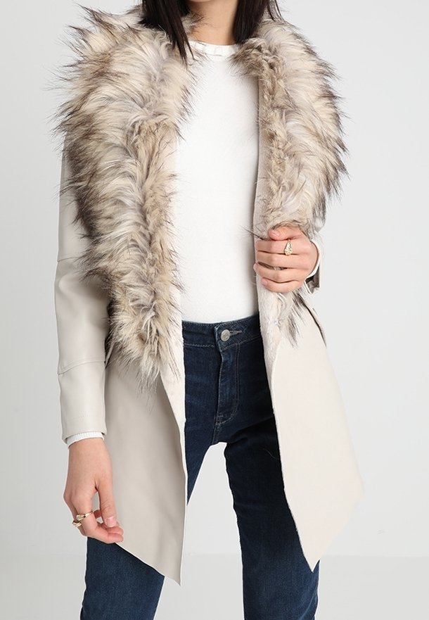 Abrigo largo beige con un cuello de piel sintética de color marrón claro. El abrigo presenta un corte ajustado y un diseño elegante, con un brillo sutil y un hardware mínimo.