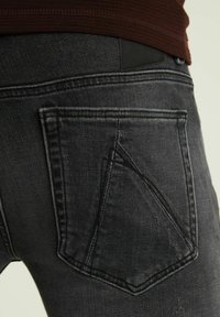 Černé džíny z denimu s texturovaným povrchem, které mají jedinečný úhlový design zadní kapsy a hladký pas.