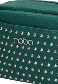 Borsa in finta pelle color teal con borchie argentate e un logo lucido. Presenta una forma rettangolare e una finitura testurizzata, con una chiusura superiore a zip.