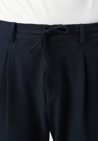 Navyblauwe textuurbroek met een elastische tailleband, verstelbaar trekkoord en twee zijzakken, met een ontspannen pasvorm en geplooid ontwerp.