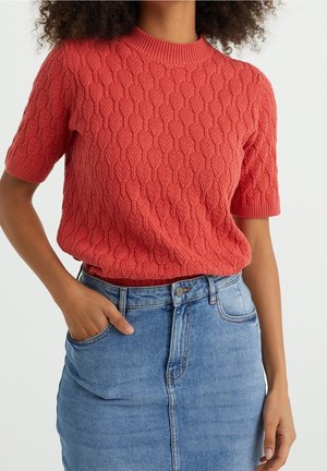 Pull corail à manches courtes avec motif texturé de feuilles et encolure côtelée, associé à une jupe en denim taille haute de couleur bleu clair.