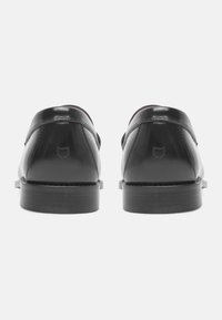 Black leather shoes with a glossy finish, rounded shape, and a wooden sole. Features a small logo on the heel and stitched detailing.