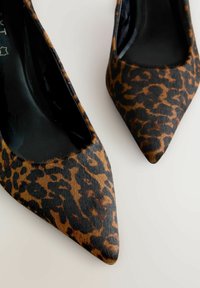 Cipele na visokom petu s uzorkom leoparda, s oštrim nosom, s teksturiranim smešom smeđe i crne boje i sjajnom crnom unutrašnjošću.