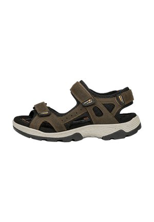 Sandalia deportiva marrón y negra con punta abierta, correas ajustables y una suela gruesa blanca y negra texturizada.