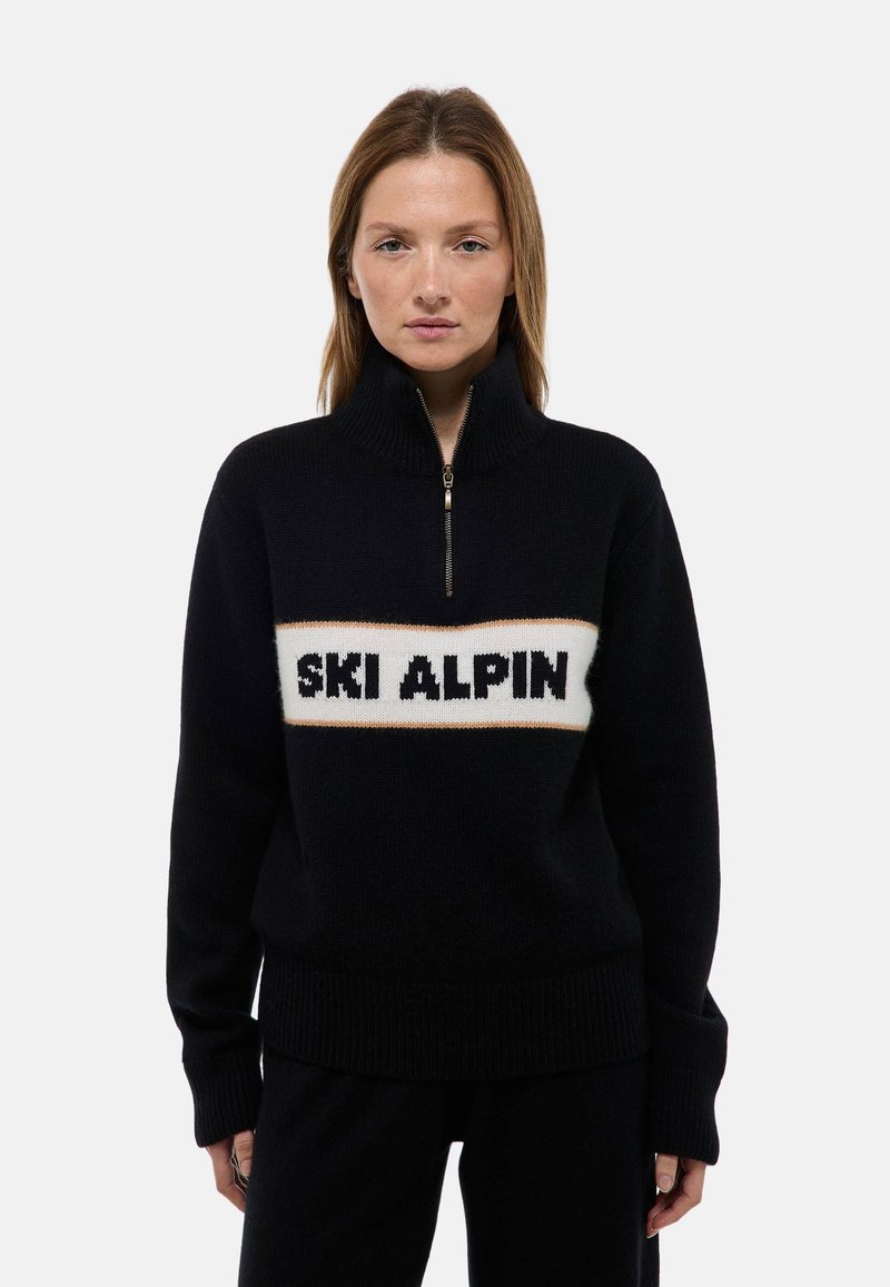 Pull noir avec un col montant, dotée d'une fermeture éclair et d'un bandeau central blanc avec "SKI ALPIN" en texte noir. Texture en maille douce.