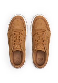 Un paio di sneakers in pelle marrone con suole bianche, allacciate, viste dall'alto su uno sfondo bianco.