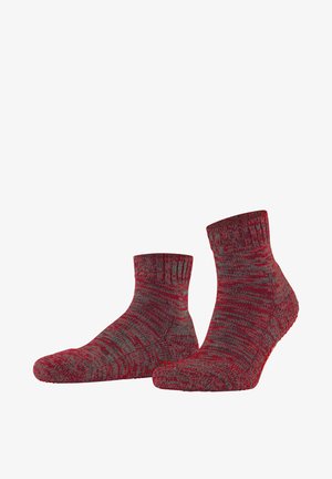Paar rot-graue, bis zur Mitte der Waden reichende Stricksocken mit strukturiertem Muster und rutschfesten Sohlen, dargestellt vor weißem Hintergrund.