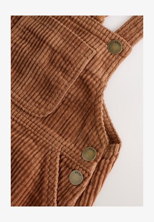 Brązowe sztruksowe ogrodniczki z pionowymi prążkami, z kieszenią na piersi i trzema mosiężnymi guzikami z napisem "NEXT". Miękka faktura o ciepłym odcieniu.