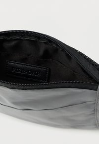 Μαύρο τσαντάκι με φερμουάρ και γκρι υφασμάτινη εξωτερική επιφάνεια. Εσωτερικό επενδυμένο με μαύρο νάιλον. Διαθέτει ανάγλυφη ετικέτα. Ομαλή υφή, συμπαγής σχεδιασμός.