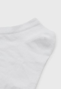 Chaussette blanche avec une texture lisse, dotée d'un bord côtelé et d'une conception de pointe sans couture. Le tissu semble doux et léger.