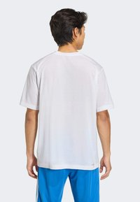 Camiseta blanca de manga corta con cuello redondo, hecha de un material suave. Diseño sencillo, ajuste holgado y sin patrones ni acentos visibles.