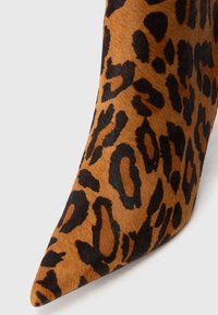 Boots s točkom, u uzorku leopard, napravljene od mekanog smešnog i crnog teksturiranog materijala. Imaju elegantan dizajn i oštar oblik nožnog prsta.