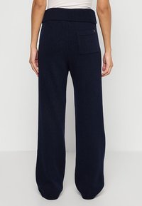 Navy wijde gebreide broek met een geribbelde elastische tailleband en één achterzak met een kleine gouden accentdetail.