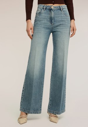 Hellblaue Jeans mit weitem Bein aus Denim, mit hoher Taille, Fronttaschen und einem dezenten Used-Effekt. Der Saum reicht bis zu den Schuhen.