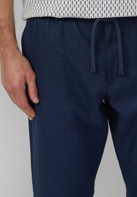 Dunkelblaue Jogginghosen aus weichem Stoff, mit lässiger Passform und seitlichen Taschen, die eine sichtbare Textur auf dem Material aufweisen.