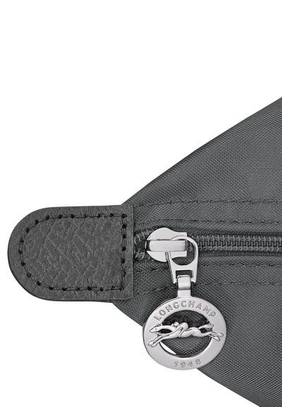 Close-up of a black fabric zipper with a silver Longchamp logo pull tab featuring a horse and "1948" engraving.
