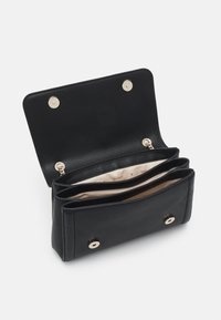 Černá texturovaná peněženka s konstrukčním designem, vybavená zapínáním na kovový zlatý klip a třemi přihrádkami uvnitř. Vystlaná béžovou látkou.