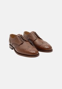 Brogues en cuir marron avec un détail perforé élaboré, bout rond et finition texturée, avec un design à lacets et un talon plat.