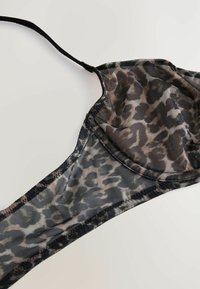 Reggiseno con stampa leopardata, realizzato in tessuto trasparente. Presenta una tracolla nera e cuciture a contrasto. Coppe sagomate con una texture liscia.