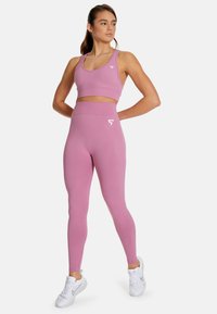 Pink athletic crop top and high-waisted leggings made of stretchy material; features a logo on the chest and back of the waistband.