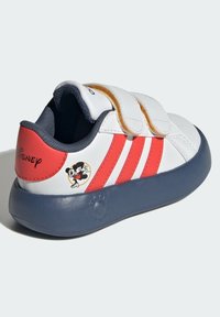 Białe dziecięce sneakersy z czerwonymi paskami, na rzepy, z granatową podeszwą. Posiadają logo Myszki Miki po boku, wykonane z materiału syntetycznego.