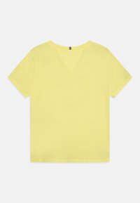 Gul T-shirt med korte ærmer fremstillet af blødt bomuld. Har en rund halsudskæring og en V-formet detalje på ryggen. Rent, enkelt design.