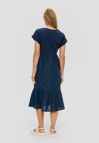 Navyblaue Baumwollkleid mit kurzen Ärmeln, einem taillierten Oberteil und einem gestuften Rüschensaum. Die Rückansicht zeigt eine taillierte Taille und ein einfaches Design.