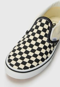 Mustreeritud must ja kreem checkerboard slip-on king, kasukate materjal, kummitald, valged õmblused, must ääreala, Vans logo küljel.