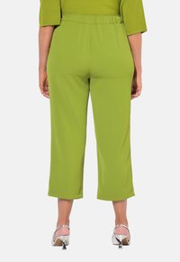 Groene, korte broek met een elastische tailleband. Grijze structuur, wijde benen en een rechte snit. Gecombineerd met zilveren block-heeled schoenen.