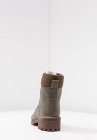 Bottechette grise avec un dessus en suède marron, un corps en cuir lisse, une semelle en caoutchouc et un talon texturé. Dispose d'une languette pour un enfilage facile.