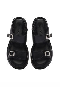 Black leather sandals featuring two adjustable straps with silver buckles. Textured insole and smooth upper, with a rounded toe design.