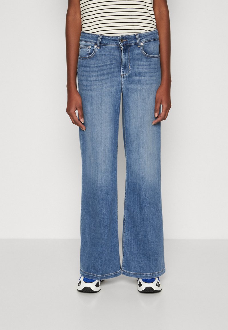 Vaqueros de corte ancho en denim de color azul claro, con un diseño clásico de cinco bolsillos, textura desgastada y un corte recto desde las caderas hacia abajo.